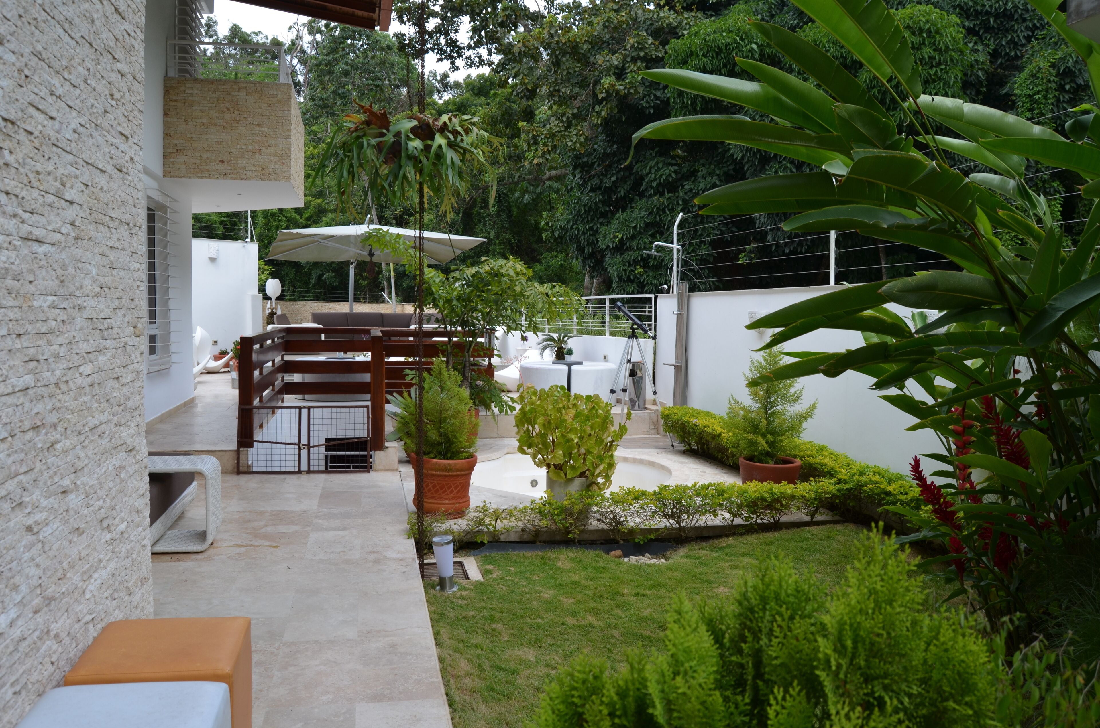 Un espace patio aménagé avec un ensemble de mobilier de jardin, des plantes en pot et une clôture blanche.