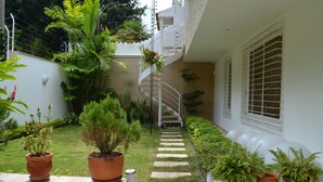 Una escalera de caracol conduce a un segundo piso, rodeada de plantas en macetas y un pequeño jardín.