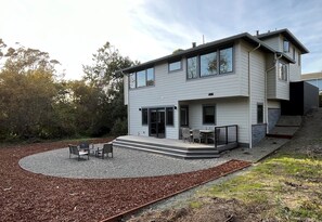 Une maison moderne à deux étages dotée d’un patio aménagé avec du mobilier d’extérieur.