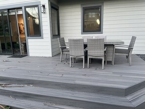 Une terrasse avec une table et des chaises, une porte-fenêtre coulissante et une fenêtre.