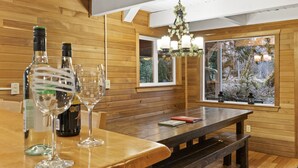 Un interior de madera con una mesa de comedor, copas de vino y botellas.