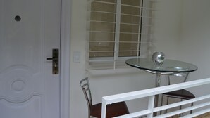A room with a white door, a window with blinds, a round glass table, and a chair. - A house with views in Caracas in a safe area I (Caracas)