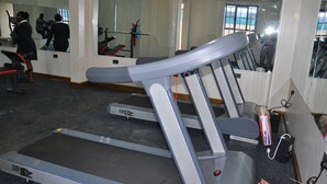 Un gimnasio con cintas de correr, un espejo grande y una ventana con vistas.