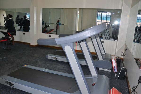 A gym with treadmills, a mirrored wall, and a window with a view.