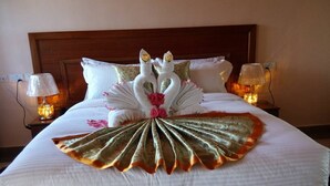 Una cama cuidadosamente arreglada con un cojín decorativo con forma de cisne y un cojín en forma de abanico.