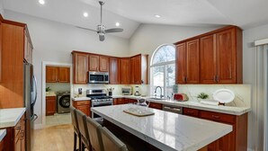 A modern kitchen with wooden cabinets, a large island, and stainless steel appliances. - Modern Salt Lake City Retreat: Spacious 5BR Home, Game Room, BBQ, Free Ski Rental, Covered Patio (Salt Lake City)