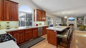 A modern kitchen with wooden cabinets, a large island, and a built-in stove. - Modern Salt Lake City Retreat: Spacious 5BR Home, Game Room, BBQ, Free Ski Rental, Covered Patio (Salt Lake City)