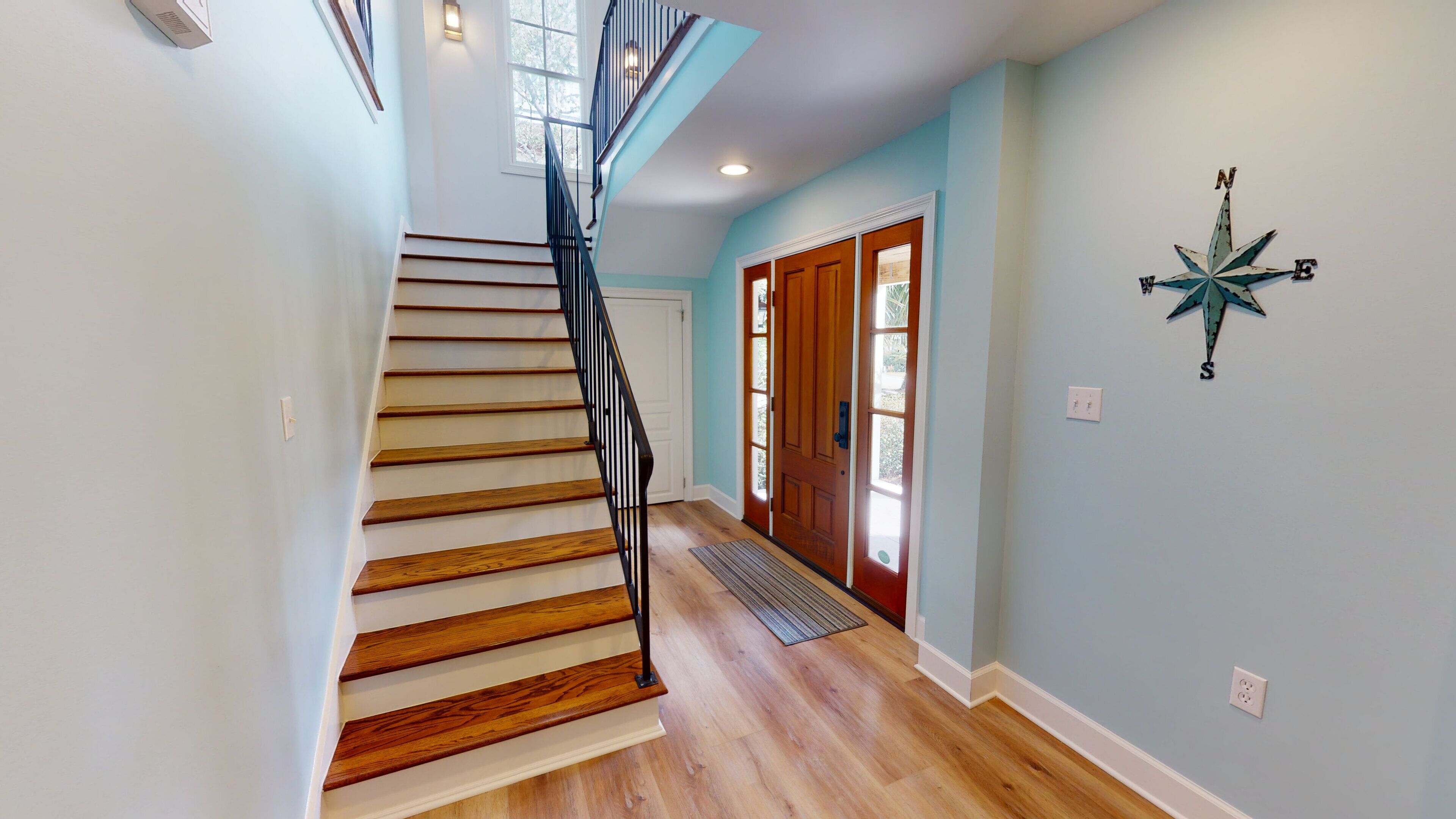 A staircase with wooden steps and a black railing leading to a door with glass panels.