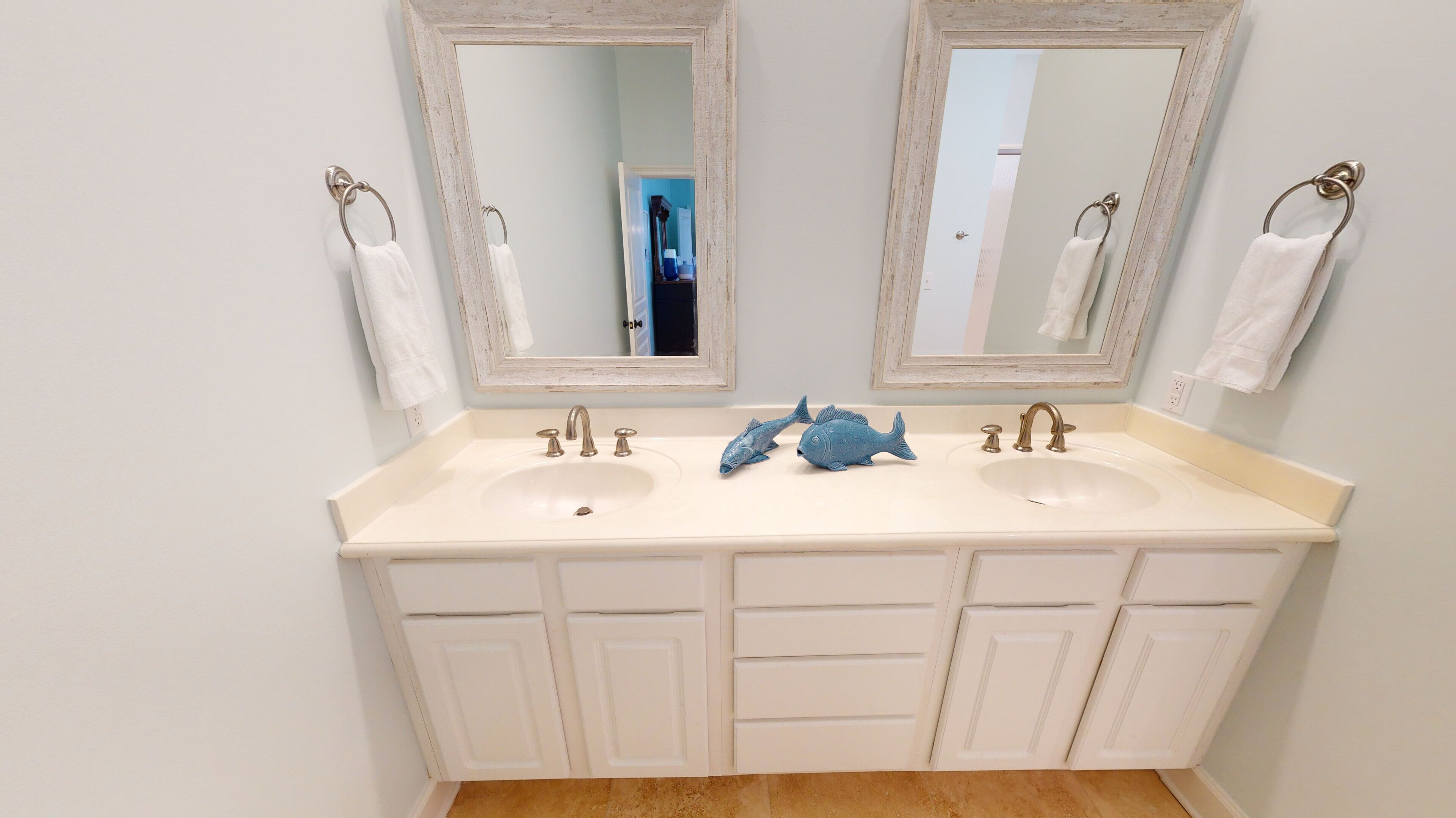 A bathroom with two sinks, two mirrors, and a decorative fish sculpture.
