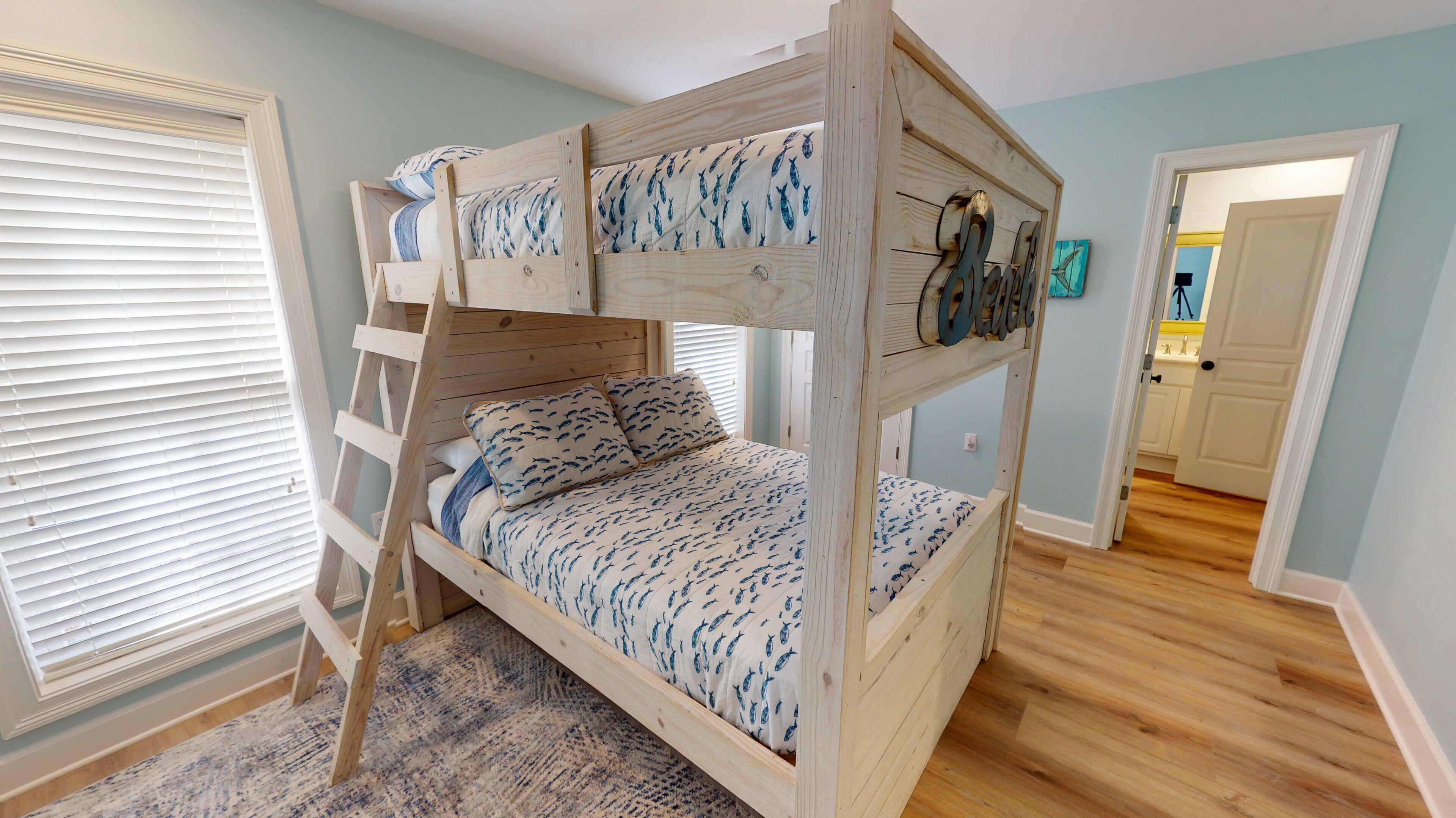 A bunk bed with a ladder, a patterned bedspread, and a wooden headboard.