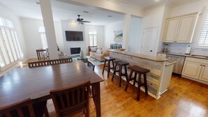 Un salón espacioso con una mesa de comedor de madera, un sofá y un televisor montado en la pared.
