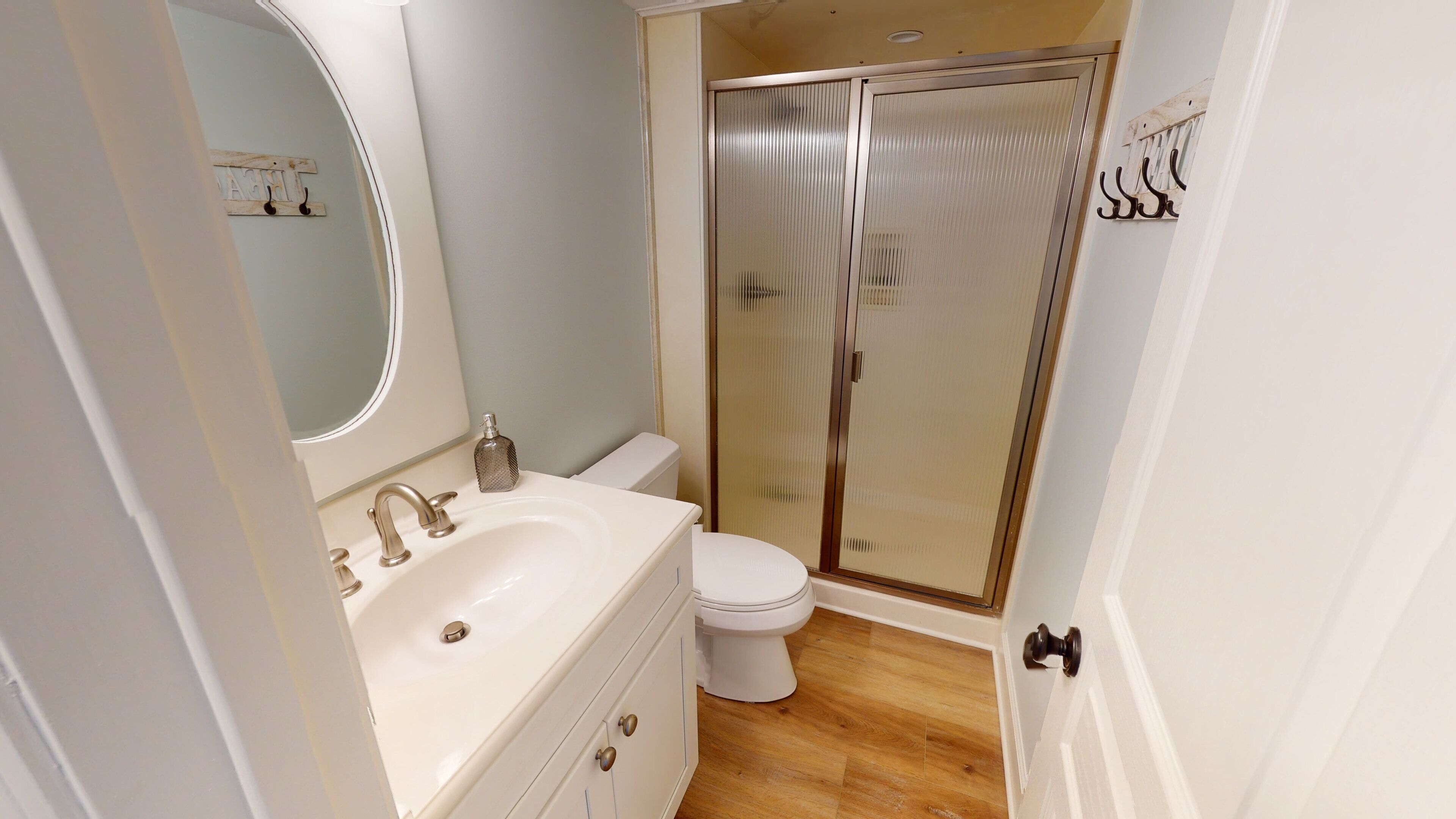 A bathroom with a white sink, a mirror, a toilet, and a glass shower enclosure.