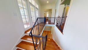 Una escalera de madera con barandillas de metal negro que lleva a un piso superior.