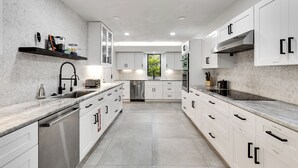 Een moderne keuken met witte kasten, een roestvrijstalen vaatwasser en een inbouwoven.