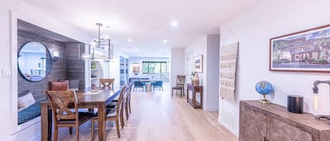 A modern kitchen with a dining area, wooden cabinets, and a view to the living room.