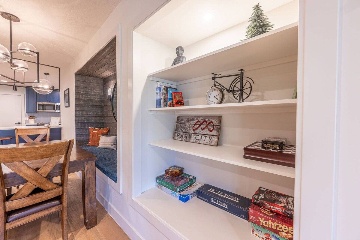 Un espacio habitable compacto con comedor, una estantería llena de objetos y una pequeña zona de estar.