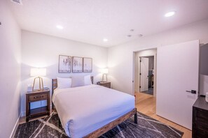 Une chambre moderne avec un grand lit, des lampes de chevet, un tapis et une porte donnant sur une salle de bain.