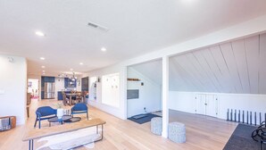 Een ruime woonkamer met een eettafel, stoelen en een bank. Achtergrond toont een keuken met moderne apparatuur.