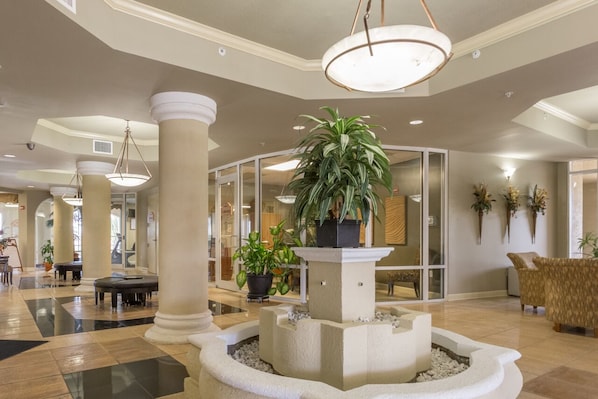 Un hall d’entrée doté d’une fontaine centrale, d’espaces aménagés pour s’asseoir et d’un comptoir d’accueil.