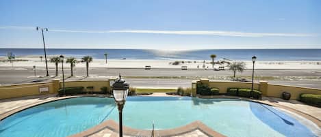 A pool area with a view of the beach and ocean.