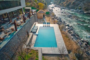 A swimming pool with lounge chairs, a small building, and a river view.