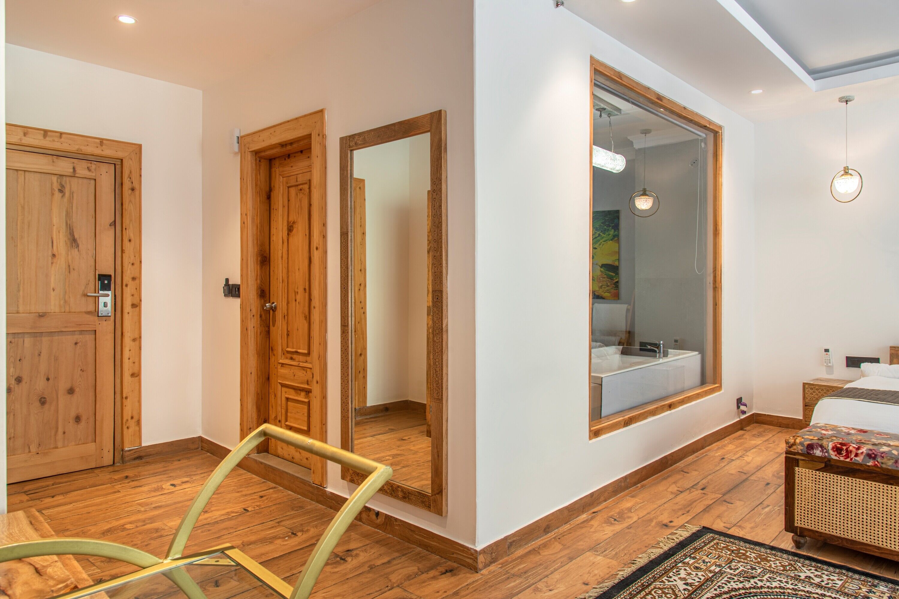 Un dormitorio moderno con suelo de madera, un espejo grande, una cama con cubrecama floral y una mesita de noche.