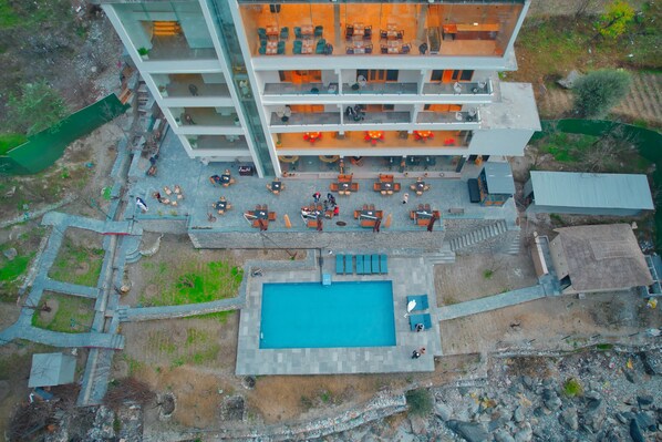 A multi-story hotel with a rooftop pool and outdoor seating area. - Echor Palm Bliss Riverside Resort & Spa Kasol (Bhuntar)