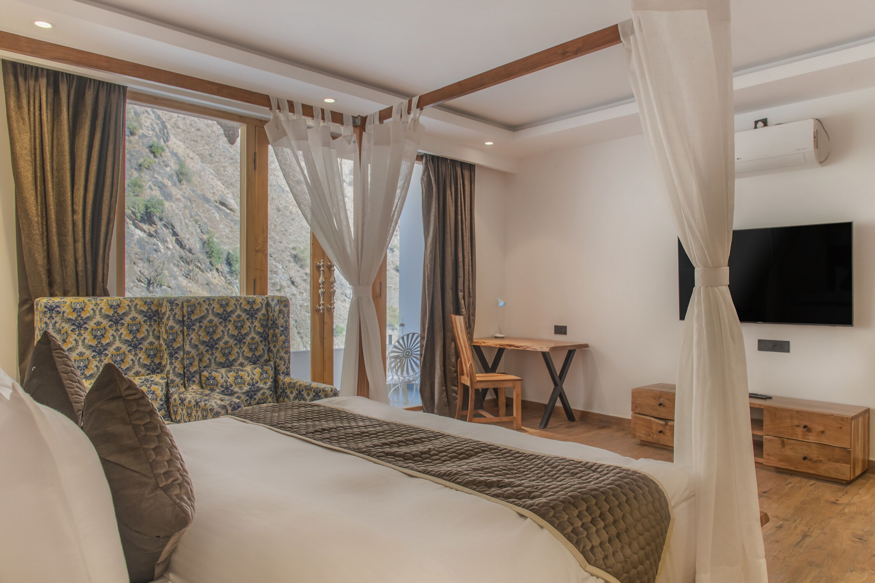 A bedroom with a bed, a desk, a chair, and a TV.