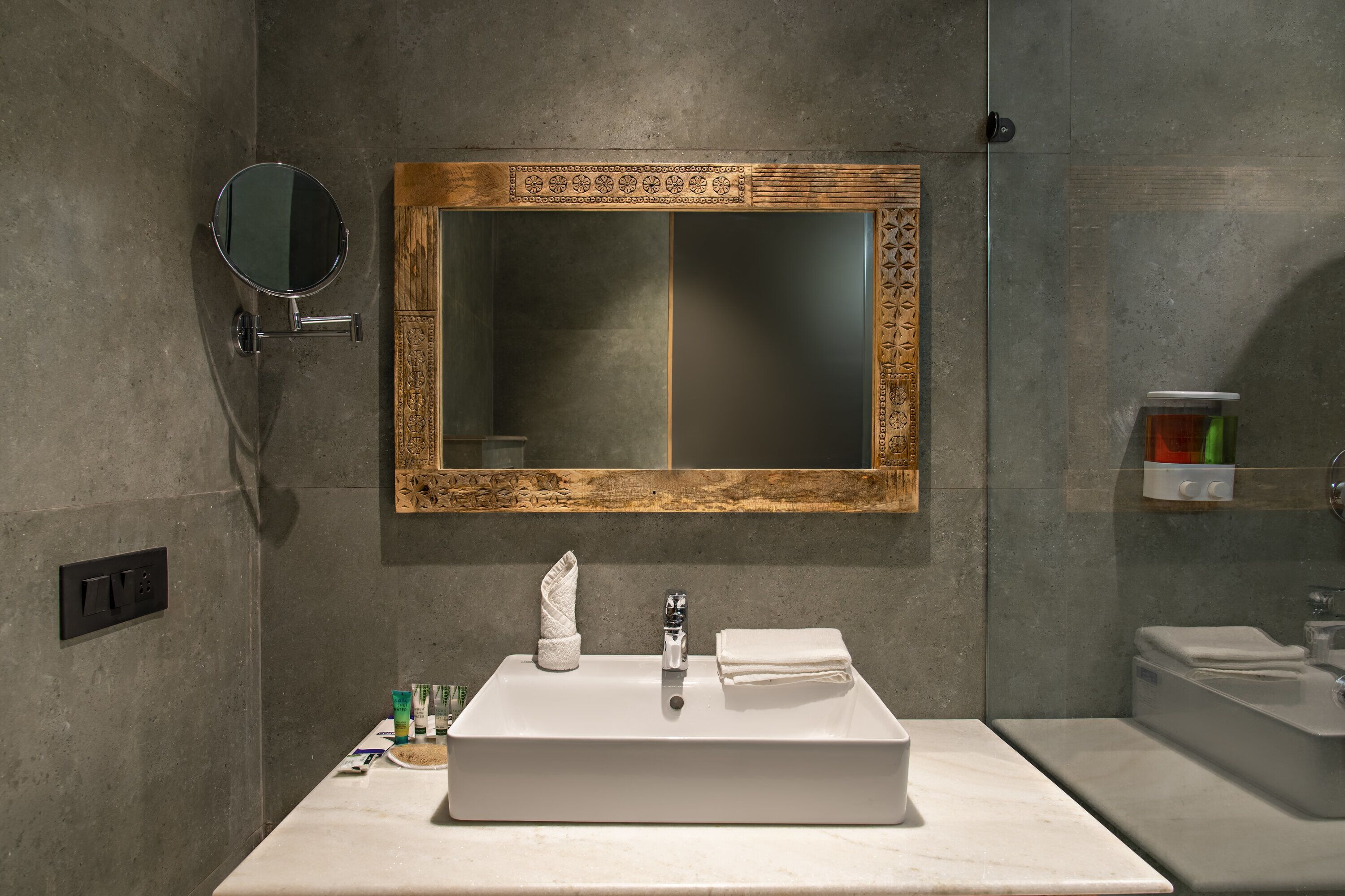 Un baño con un lavamanos rectangular, un espejo con un marco decorativo y un perchero para toallas.