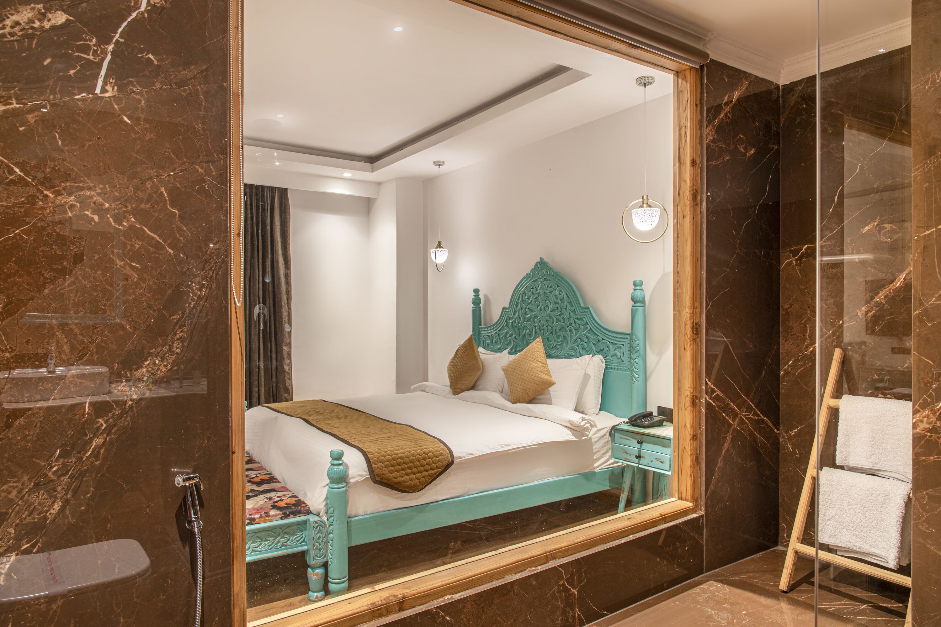 Une chambre avec un grand miroir, un lit avec une tête de lit en bois, une table de chevet et une échelle en bois pour les serviettes.