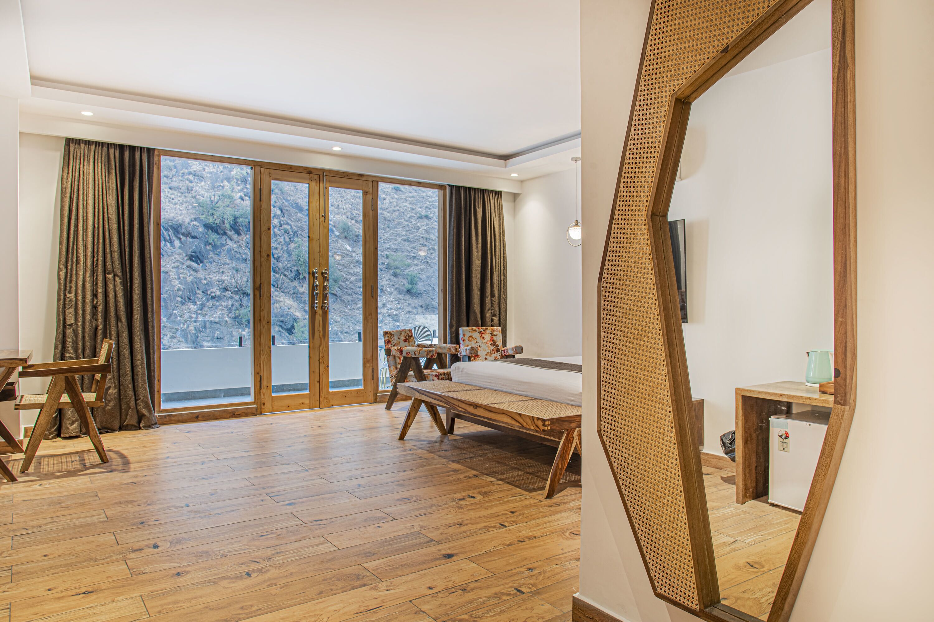 Une pièce spacieuse avec un plancher en bois, un lit, un bureau et une chaise.