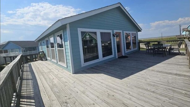 A light blue building with large windows and a wooden deck. - Cozy and Clean steps from the beach. Gulf views <3 (Freeport)