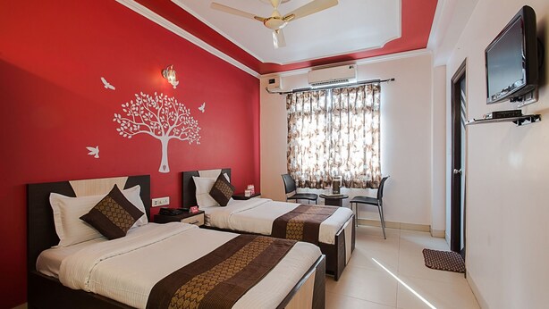 A hotel room with two beds, a ceiling fan, a TV, and a window with curtains. - OYO Rooms Sindhi Camp Metro Station 2 (Jaipur)