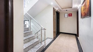 A hallway with a carpeted floor, a staircase with metal railings, and a 'No Smoking' sign on the wall. - OYO Rooms Sindhi Camp Metro Station 2 (Jaipur)