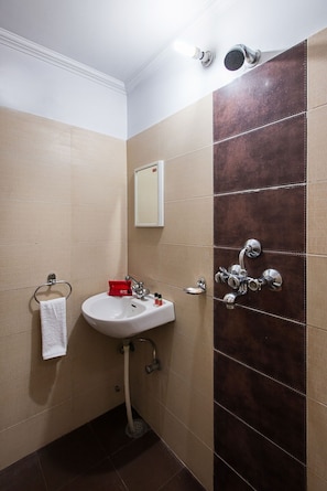 Un baño con un lavamanos blanco, un espejo y una ducha con grifo de cromo.