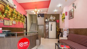 A hotel reception area with a glass counter, a reception desk, a staircase, and a seating area with a sofa. - OYO Rooms Sindhi Camp Metro Station 2 (Jaipur)