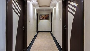 A hallway with dark wooden doors, a beige carpet, and a painting on the wall. - OYO Rooms Sindhi Camp Metro Station 2 (Jaipur)