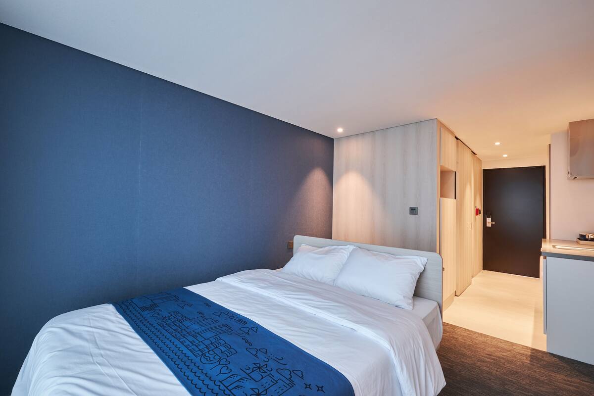 Une chambre d’hôtel moderne avec un grand lit, un bureau et une armoire.