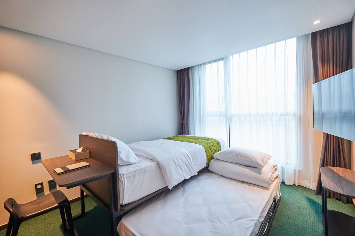 Une chambre d’hôtel avec un lit, un bureau, une chaise et un téléviseur.