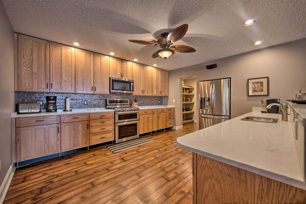 Una cocina moderna con armarios de madera, electrodomésticos de acero inoxidable y una isla grande con un fregadero.
