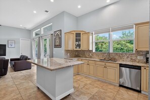 A modern kitchen with a central island, built-in cabinets, and a stainless steel dishwasher.