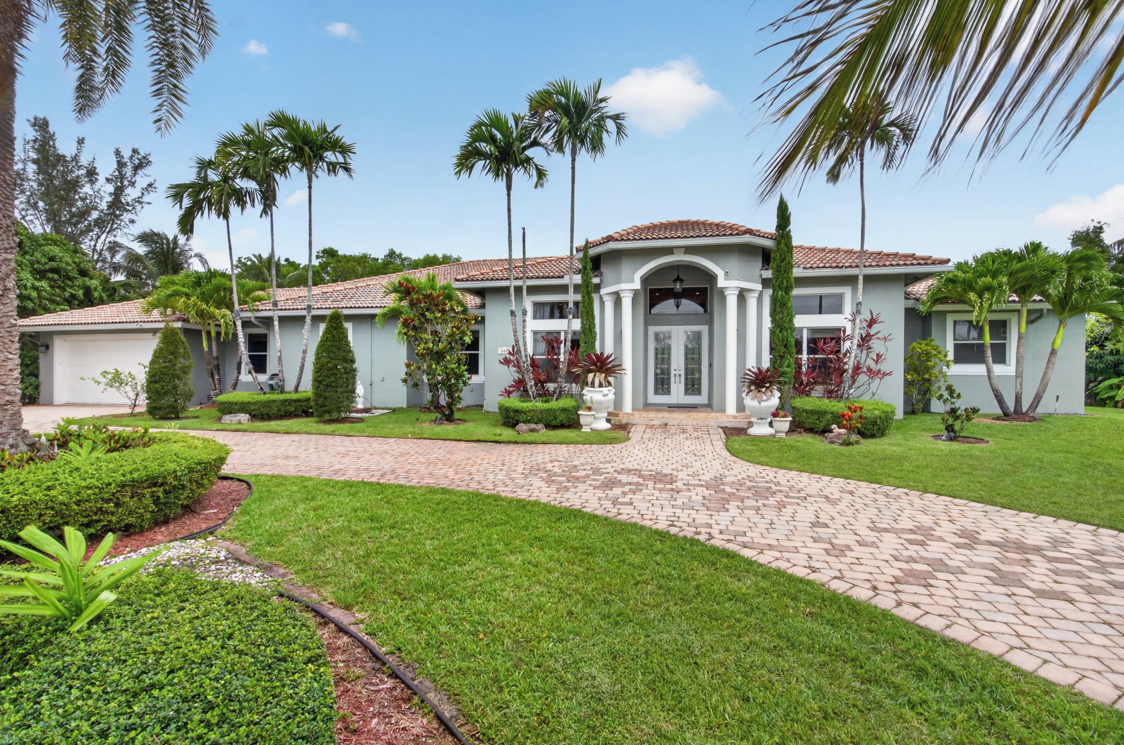 A two-story house with a tiled roof, a front entrance with a door, and a paved driveway leading to the entrance.