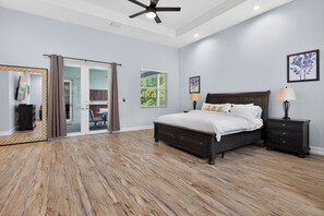 A bedroom with a large bed, a ceiling fan, and a sliding glass door leading to a patio.