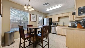 A kitchen with a dining table, chairs, a refrigerator, microwave, and a coffee machine. - Modern Pflugerville Home Near Austin and Tech Hub (Pflugerville)