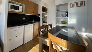 Eine kompakte Küche mit Holzausbau, einer Mikrowelle, einem Spülbecken, einem Geschirrspüler und einem Esstisch mit Stühlen.