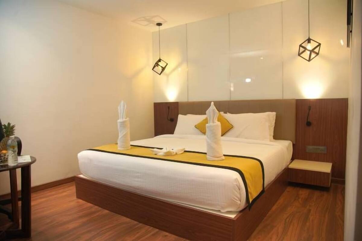 A hotel room with a large bed, wooden headboard, and bedside tables.