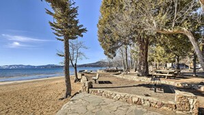 Un parque frente al mar con senderos de piedra, mesas de picnic y bancos.