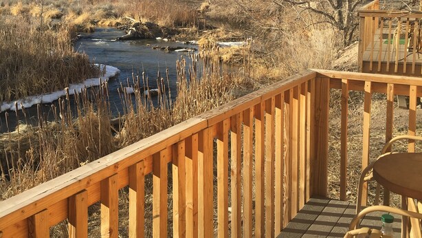 A wooden deck with a view of a river and surrounding landscape.
