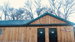 A wooden building with two doors labeled "SHOWERS" and "REST ROOMS".