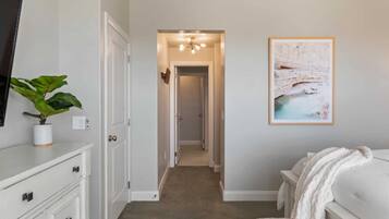 A bedroom with a bed, a bedside table, a nightstand, a wall-mounted TV, a framed picture, and a plant.